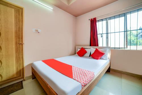 um quarto com uma cama com almofadas vermelhas e uma janela em Flagship Hotel Mayur em Dalaigaon