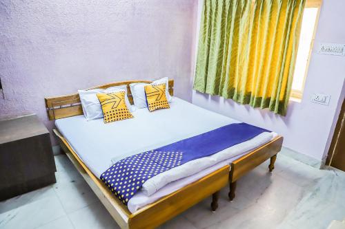 a bed with yellow and blue pillows and a window at SPOT ON Nanki Palace in Ajmer