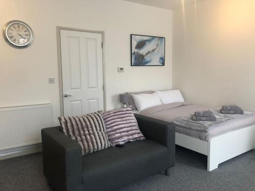 a bedroom with a bed and a chair and a clock at Newly Renovated Modern Studio Apartment in Penzance