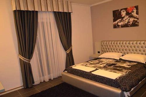 a bedroom with a bed and a window with curtains at Hotel Mustang in Tirana
