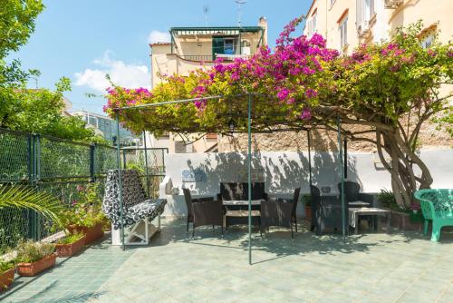 un patio con tavolo, sedie e fiori di Villa dei Sogni - Aparthotel Ischia Ponte a Ischia