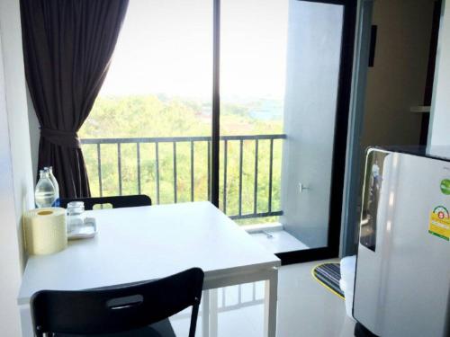 Una mesa blanca y sillas en una cocina con balcón. en Promsook Apartment en Bangsaen