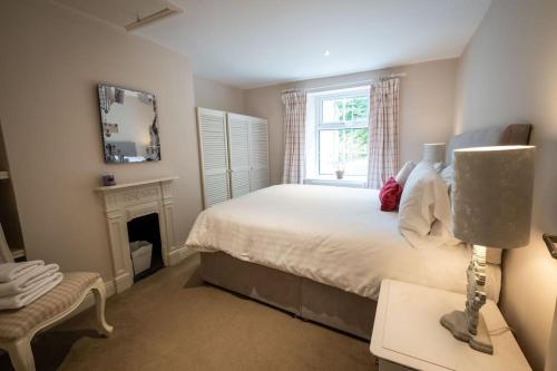 Apple Cottage -- Luxury Stay @ Bellingham Castle في كاستيلبيلينغهام: غرفة نوم بسرير ومدفأة ونافذة