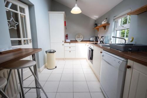 Apple Cottage -- Luxury Stay @ Bellingham Castle في كاستيلبيلينغهام: مطبخ مع أرضية بلاط أبيض ومغسلة