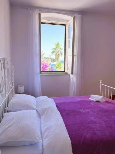 a white bedroom with a purple bed with a window at Zamaria Apartments in Vis