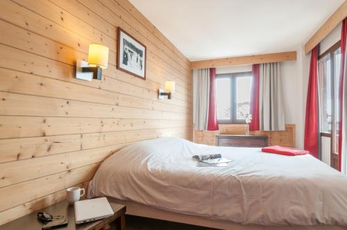1 dormitorio con 1 cama y paredes de madera en Résidence Pierre & Vacances Saskia Falaise, en Avoriaz