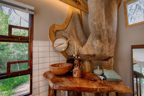 uma casa de banho com um lavatório de madeira e um espelho em Elsewhere Treehouse and Apartment on the River em Muldersdrift