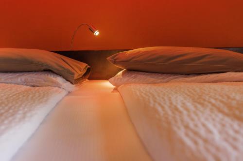 two beds with pillows in a room with a lamp at Ambienthotel PrimaLuna 3S in Malcesine