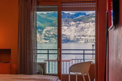 a bedroom with a view of the water and mountains at Ambienthotel PrimaLuna 3S in Malcesine