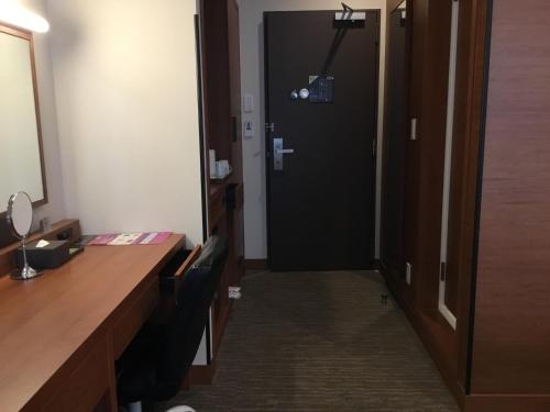 a door leading into a room with a desk and a desk at Odysis Suites Osaka Airport Hotel in Izumi-Sano