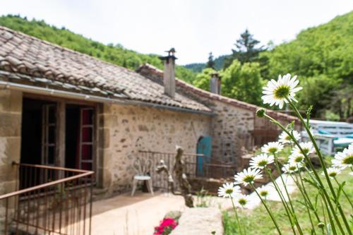 a small stone house with a patio and flowers at Auberge de Lascours in Ceilhes-et-Rocozels