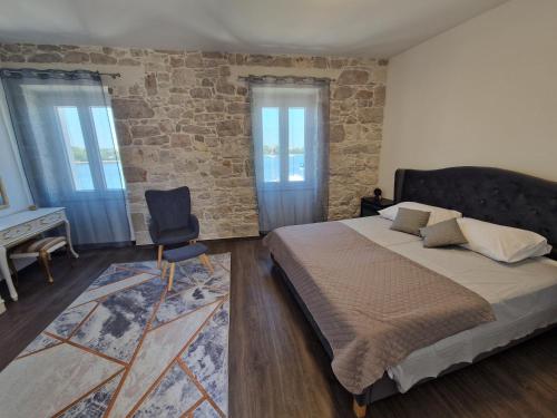 a bedroom with a large bed and a stone wall at Villa Galleria in Sukošan