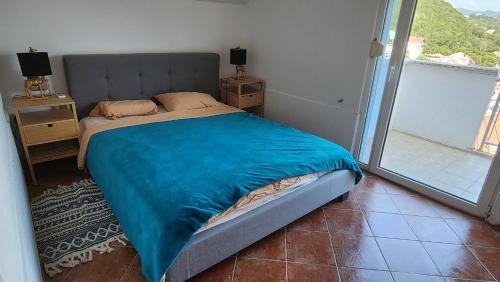 1 cama con manta azul en una habitación con ventana en Altvarg, en Igalo