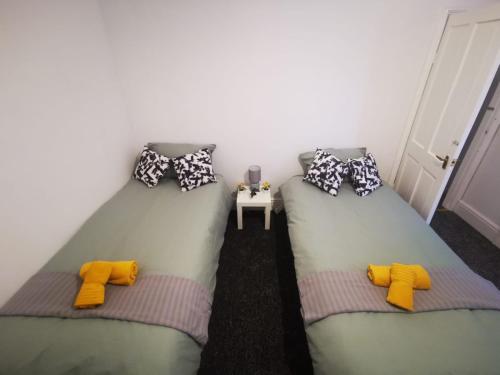 2 bedden in een kamer met gele en grijze kussens bij Twin Room - Sutherland Place in Derby