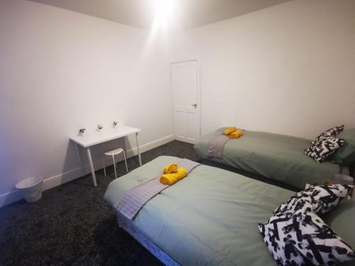 two beds in a room with a table and a desk at Twin Room - Sutherland Place in Derby