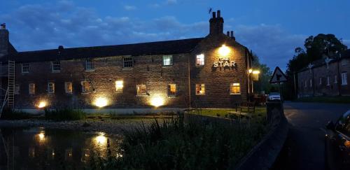 an old brick building with lights on it at night at The Star Inn in North Dalton