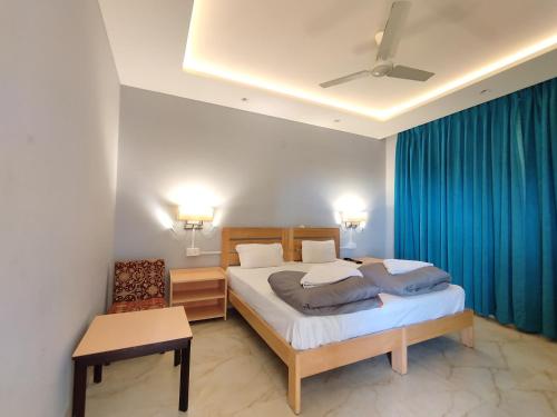 a bedroom with two beds and a blue curtain at Madpackers Bir in Bīr
