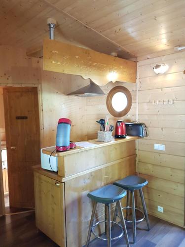 a kitchen with two stools at a counter in a cabin at Le Village de la Champagne - Slowmoov in Bar-sur-Aube