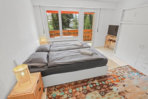 Bett in einem Zimmer mit Fenster in der Unterkunft Studio paisible et chaleureux in Crans-Montana