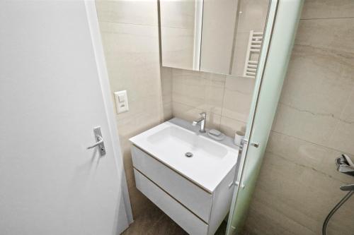 ein Badezimmer mit einem weißen Waschbecken und einem Spiegel in der Unterkunft Studio paisible et chaleureux in Crans-Montana
