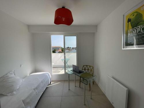 une chambre avec un lit et un bureau avec un ordinateur portable dans l'établissement Superbe appart à 10m de la plage, 2 terrasses, 3 chambres, vue océan - FR-1-494-163, à Royan