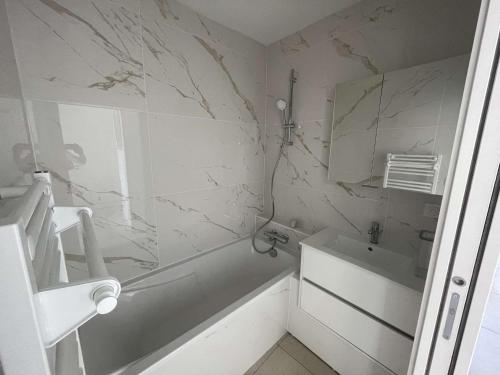 une salle de bain blanche avec une baignoire et un lavabo dans l'établissement Superbe appart à 10m de la plage, 2 terrasses, 3 chambres, vue océan - FR-1-494-163, à Royan