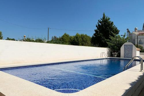 een zwembad naast een witte muur bij Villa familiar en la montaña, con acceso a piscina in Denia