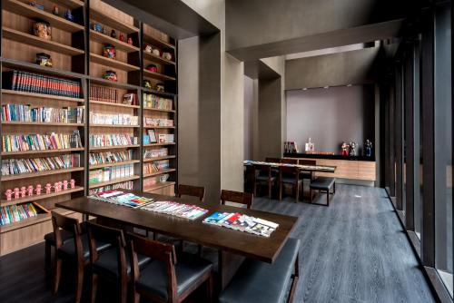uma biblioteca com mesa, cadeiras e estantes em Just Sleep Hualien ZhongZheng em Hualien