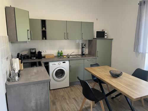a kitchen with a washing machine and a table with chairs at Apartment 2 - Haus Lausitzring in Annahütte