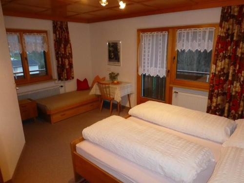 1 dormitorio con 2 camas, mesa y ventanas en Haus Salzmann en Sankt Gallenkirch