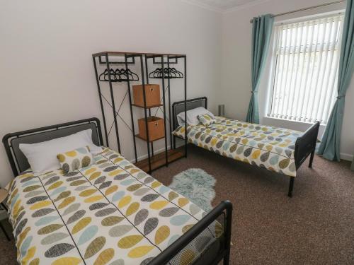 1 dormitorio con 2 camas y ventana en Brynawel en Burry Port