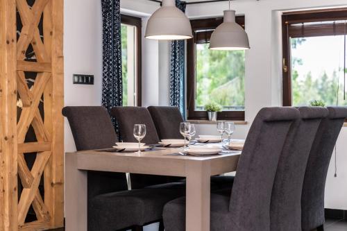a dining room with a table and chairs with wine glasses at TatryTop Alpejski SPA in Kościelisko