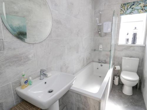 a bathroom with a sink and a toilet and a mirror at Branwen in Talacre