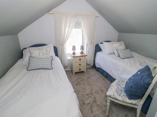 a attic bedroom with two beds and a window at Branwen in Talacre