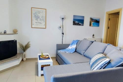 a living room with a blue couch and a tv at Simply Meraki Gytheian apt with Panoramic Sea View in Gythio
