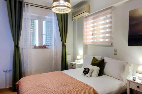 a bedroom with a bed and two windows and a chandelier at Simply Meraki Gytheian apt with Panoramic Sea View in Gythio