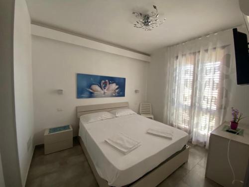 a white bedroom with a bed and a window at Casa Diamante in San Vito lo Capo