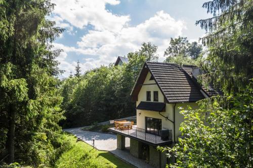 a house in the middle of a forest with a balcony at TatryTop Alpejski SPA in Kościelisko