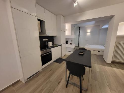 uma cozinha com armários brancos e uma mesa e cadeira pretas em Apartment Near The Center Of Glyfada em Atenas