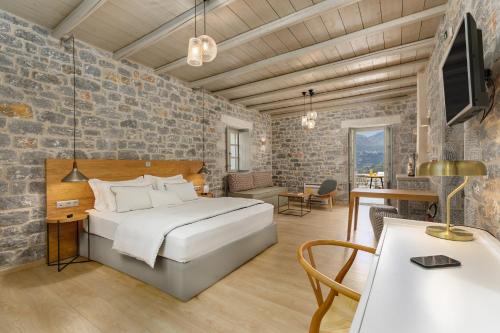 Trapela Limeni Luxury Suites في ليميني: غرفة نوم بسرير وطاولة وكراسي