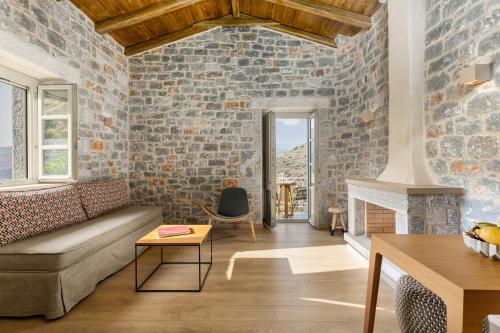 a living room with a couch and a brick wall at Trapela Limeni Luxury Suites in Limeni