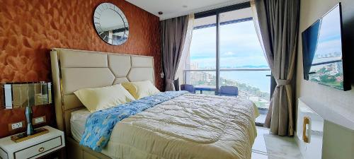 a bedroom with a bed and a large window at Seaview Beachfront Skypool Rooftop Copacabana Jomtien Condo in Jomtien Beach