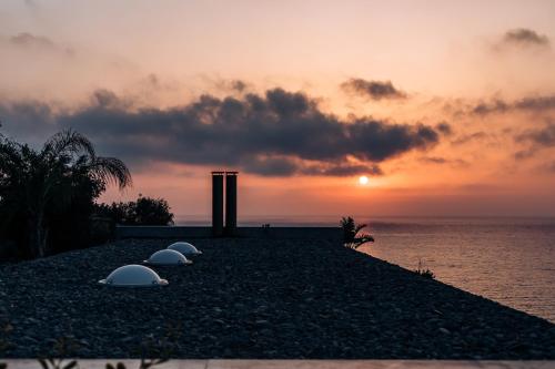 a sunset over the ocean with three domes on a beach at Villa Aquamarine in Pomos