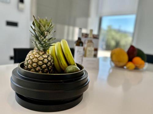 a black bowl with a pineapple and other fruits on a counter at LeBlanc Luxurious Beachfront Villa by Goutos Luxury Living in Ermioni