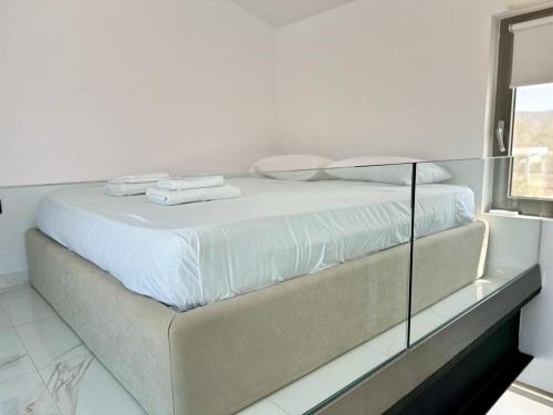a white bedroom with a large bed with white sheets at LeBlanc Luxurious Beachfront Villa by Goutos Luxury Living in Ermioni