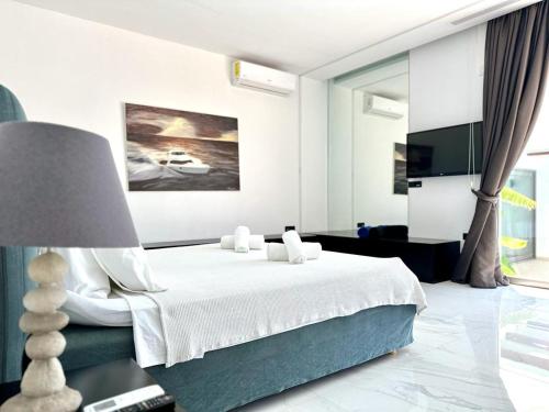 a white bedroom with a bed and a lamp at LeBlanc Luxurious Beachfront Villa by Goutos Luxury Living in Ermioni