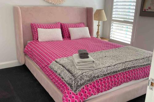 Cama rosa con manta rosa y almohadas en Bowral Retreat, en Bowral
