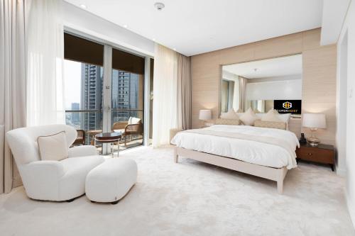 - une chambre avec un grand lit blanc et une chaise dans l'établissement SuperHost EMAAR Residences Fashion Avenue - Address Dubai Mall, à Dubaï