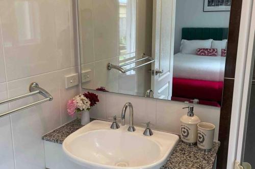 a bathroom with a sink and a mirror and a bed at Bowral Retreat in Bowral