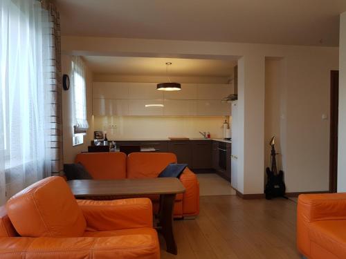 a living room with orange furniture and a kitchen at Wigilijna Apartament in Lublin